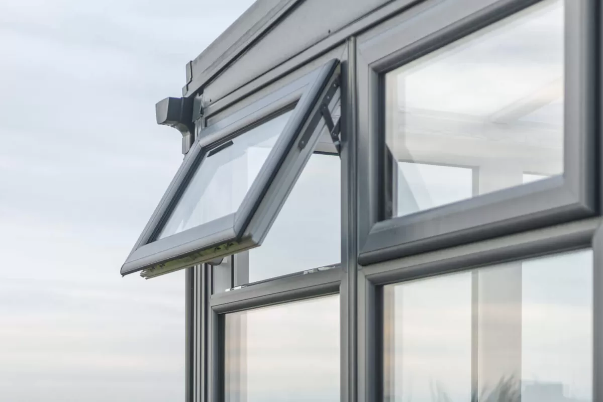 Exemplo de aplicação prática de uma esquadria: janela do tipo maxim-ar com caixilho de alumínio grafite, aberta, ideal para ventilação em banheiros e cozinhas.