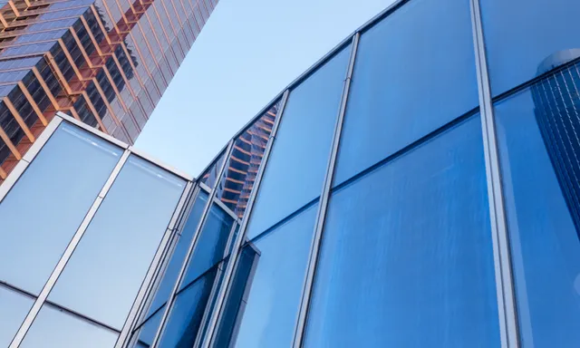 Fachada de um edifício moderno com painéis de vidro azulado, ilustrando a variedade de escolhas estéticas para um projeto arquitetônico.