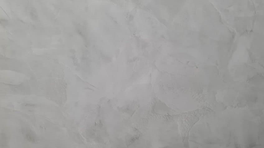 Textura de uma parede com acabamento em cimento queimado na cor cinza, mostrando as nuances e manchas características do estilo industrial.