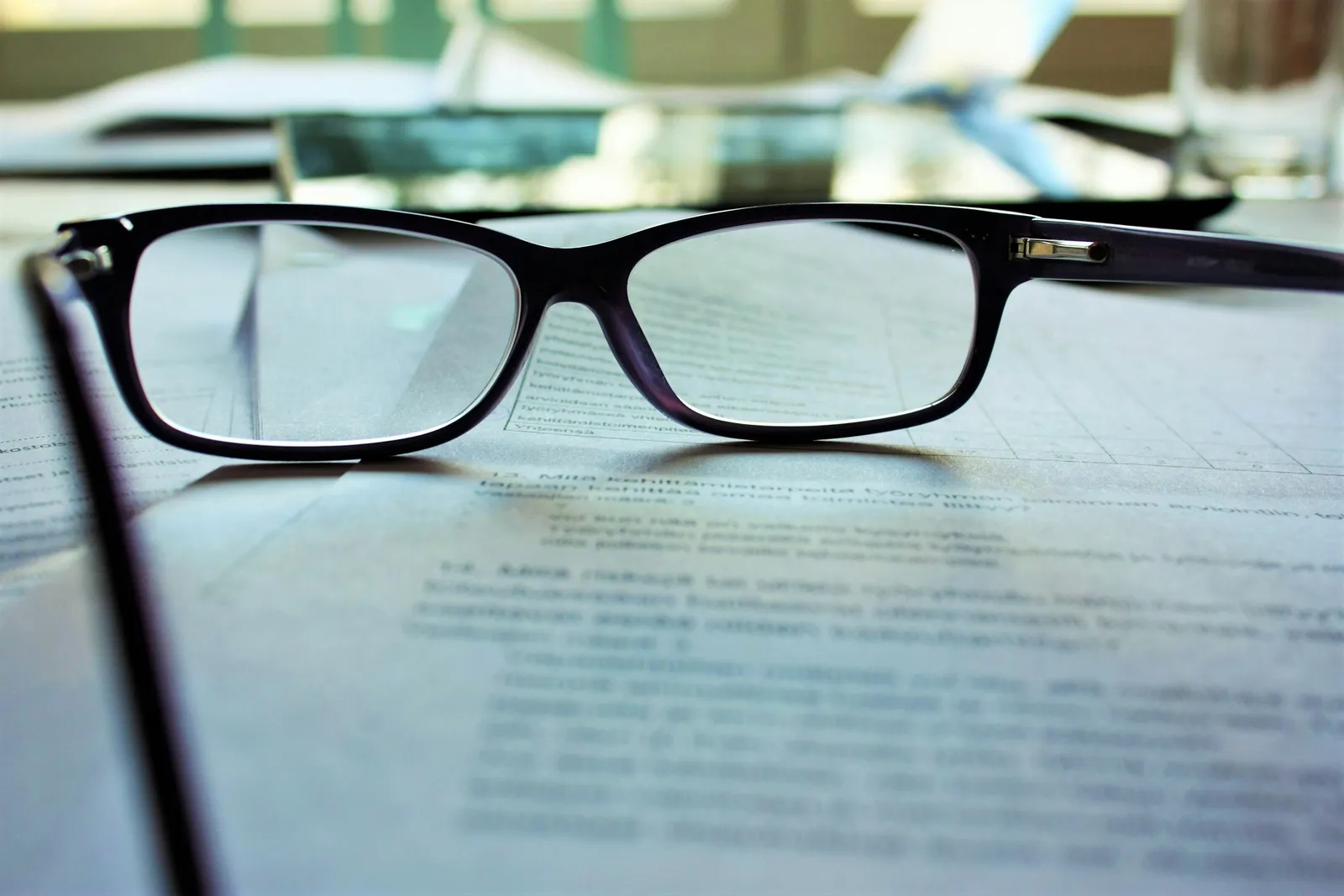 Óculos apoiados sobre documento com cláusulas contratuais prontas para revisão antes da assinatura