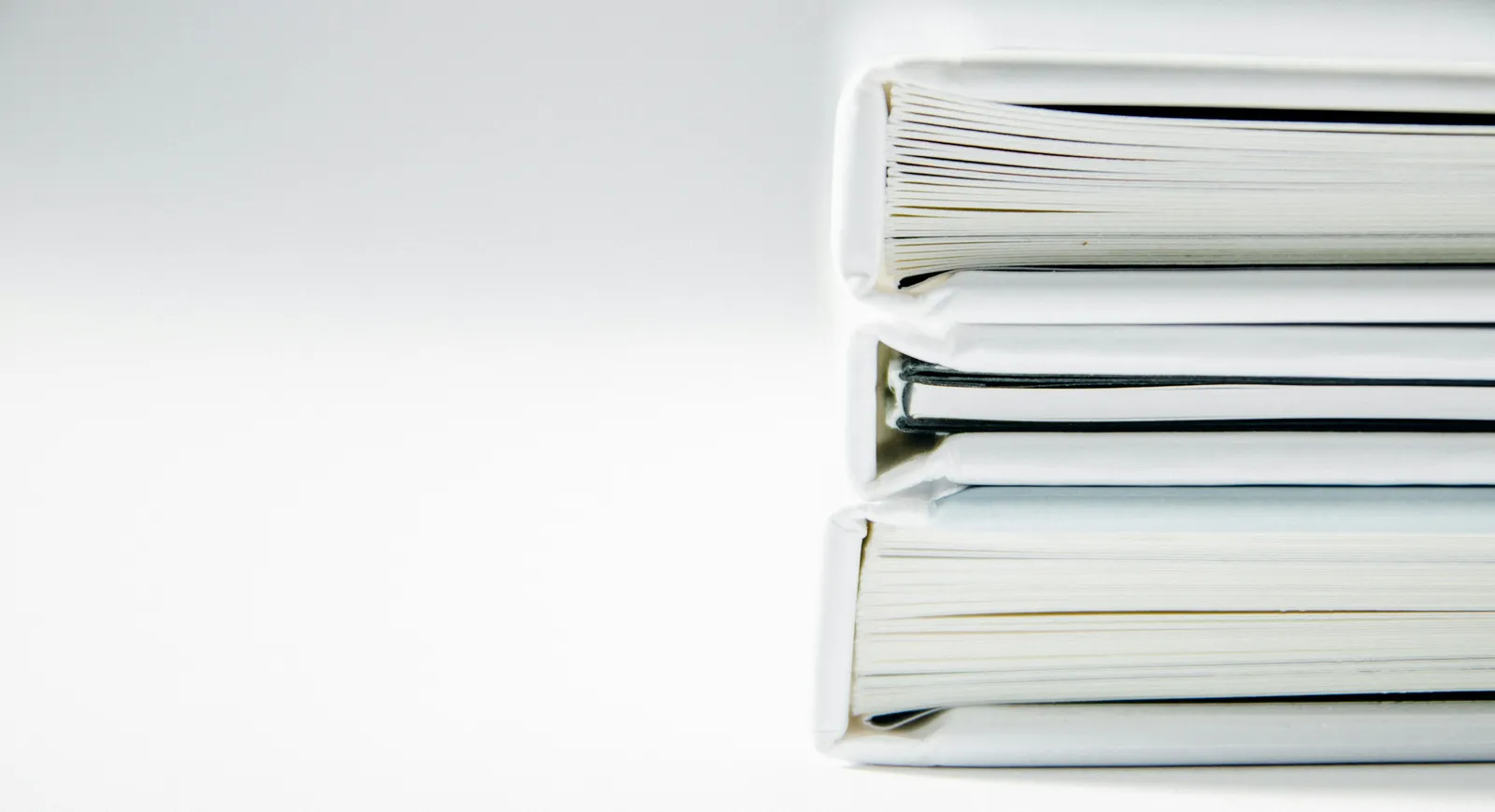 Pilha de pastas e propostas de contrato empilhadas sobre a mesa, representando a comparação de propostas de manutenção predial antes da contratação