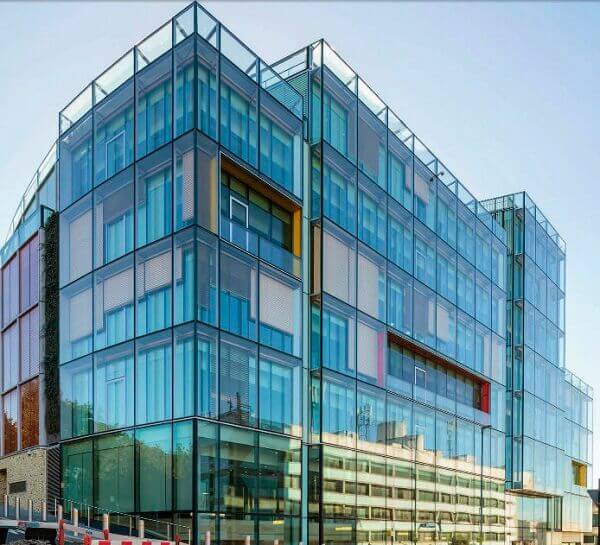 Edifício comercial com sistema de fachada dupla pele de vidro, mostrando a camada externa de vidro e o vão de ar antes da camada interna do prédio, solução para eficiência energética.