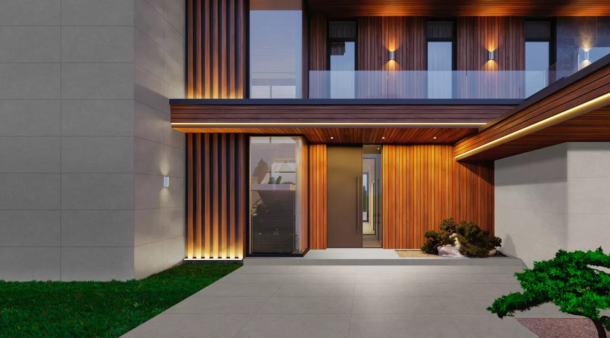 Fachada de uma casa moderna à noite, com iluminação embutida destacando o revestimento de madeira ripada, painéis de cimento queimado e a porta de vidro.