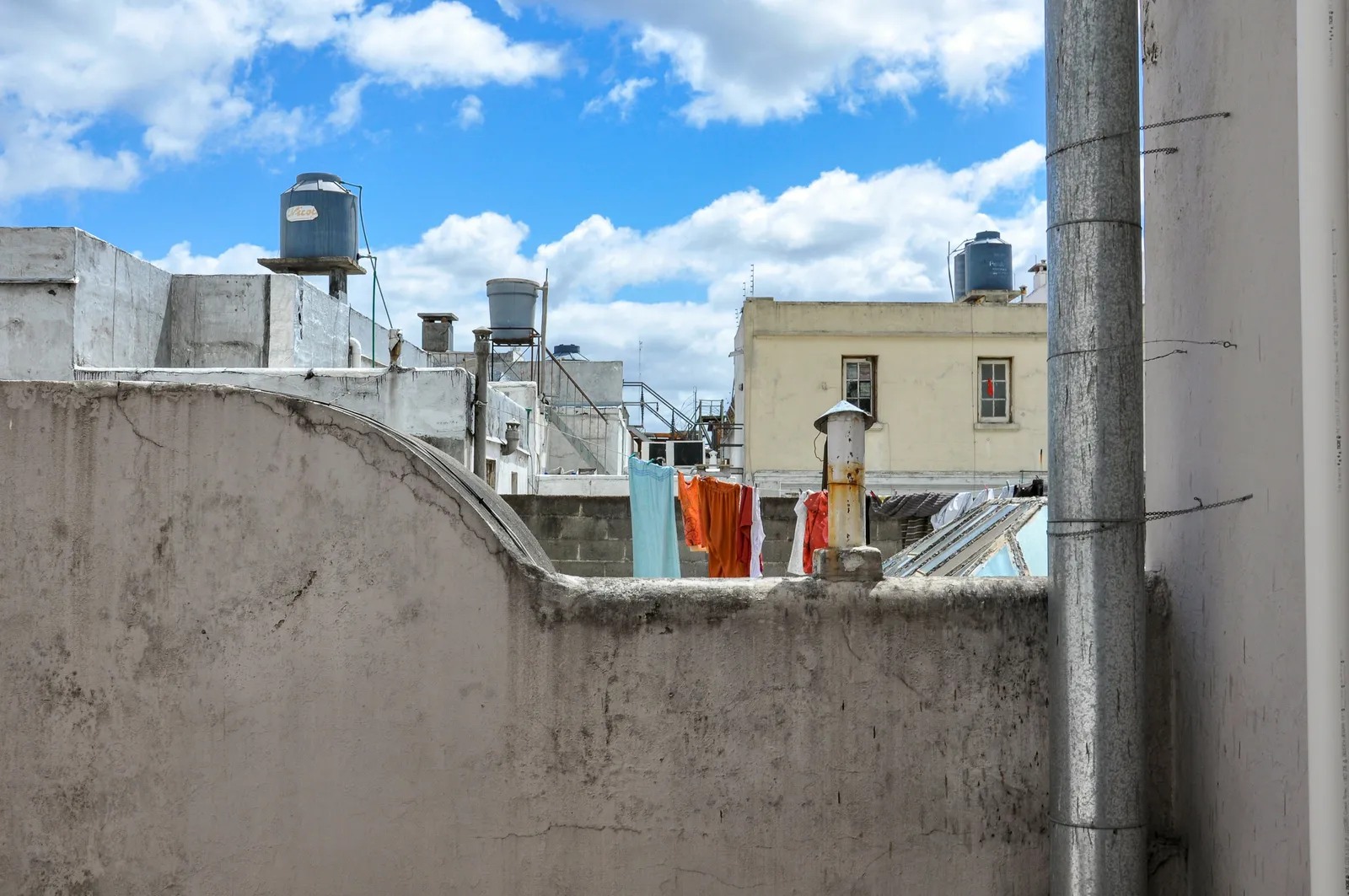 Terraço de prédio residencial com caixas d'água de polietileno instaladas ao lado do varal, reservatórios que dependem de limpeza semestral obrigatória