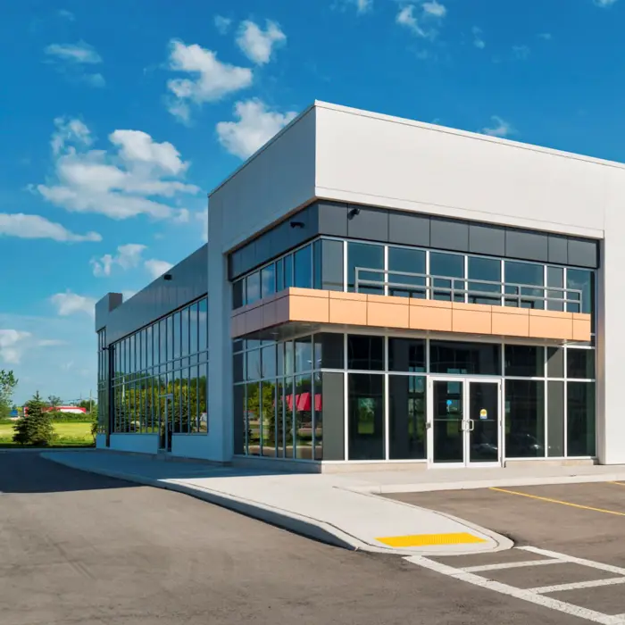 Como Escolher o Toldo Ideal para a Fachada da sua Loja Fachada de um comércio com um toldo retrátil listrado em preto e branco sobre a porta e as janelas, conferindo um estilo clássico e elegante à loja.