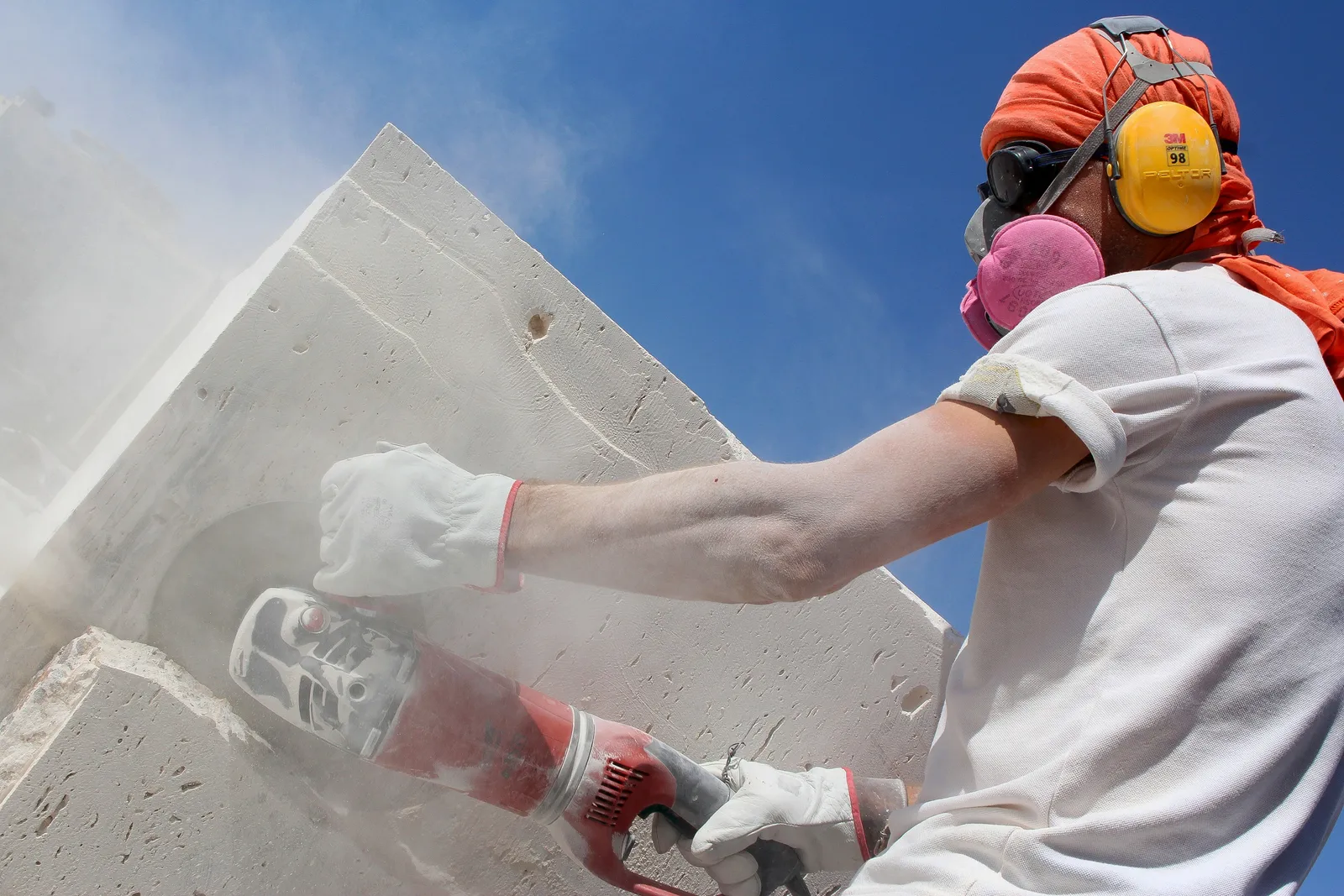 Profissional com equipamento de proteção usa esmerilhadeira em peça de concreto durante um reparo de manutenção predial