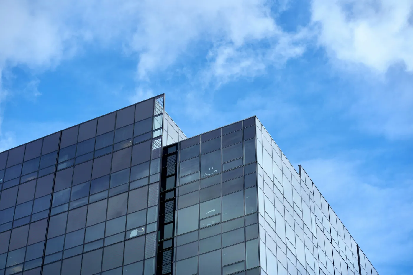 Fachada de vidro em edifício moderno com reflexo do céu, exemplo de aplicação de controle solar