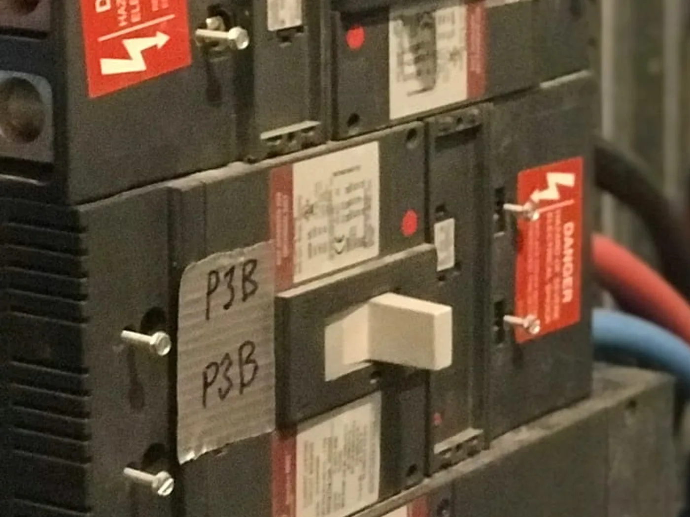 Disjuntor identificado como P3B em quadro elétrico predial, com cabos elétricos vermelho e azul ao lado