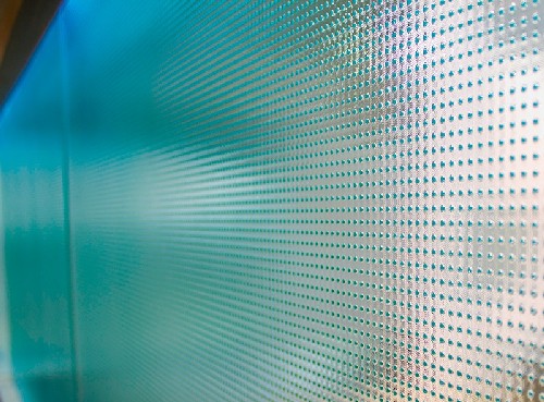 Detalhe de um vidro fantasia do tipo pontilhado, mostrando o padrão em relevo na superfície que é usado em portas, janelas e box de banheiro