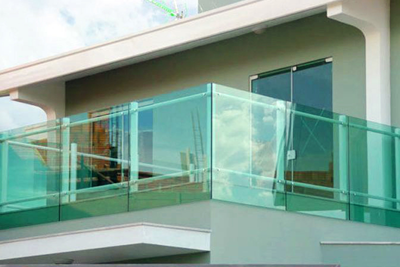 Guarda-corpo de vidro temperado verde em uma sacada de sobrado, com estrutura de alumínio e corrimão, garantindo segurança e design moderno.