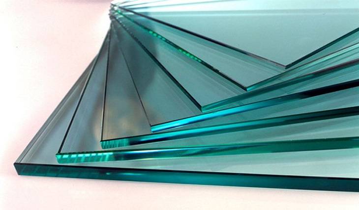 Chapas de vidro temperado incolor empilhadas, mostrando a espessura e a característica borda com tonalidade esverdeada do material