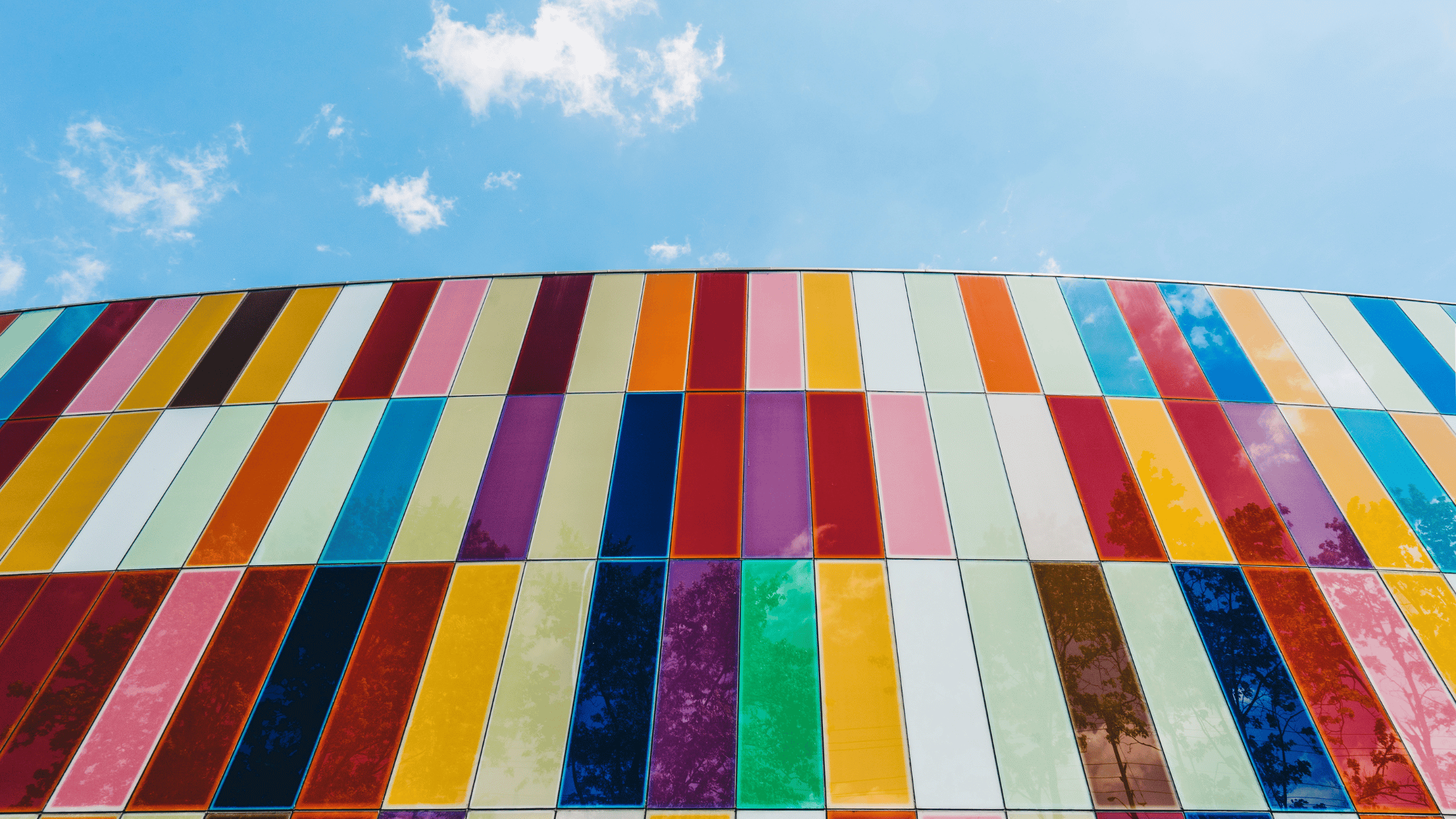 Fachada de edifício com painéis de vidro temperado de várias cores e texturas.