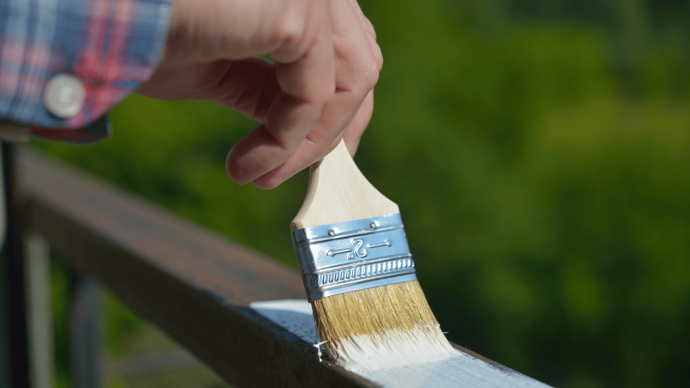 Pessoa pintando guarda-corpos com tinta branca.