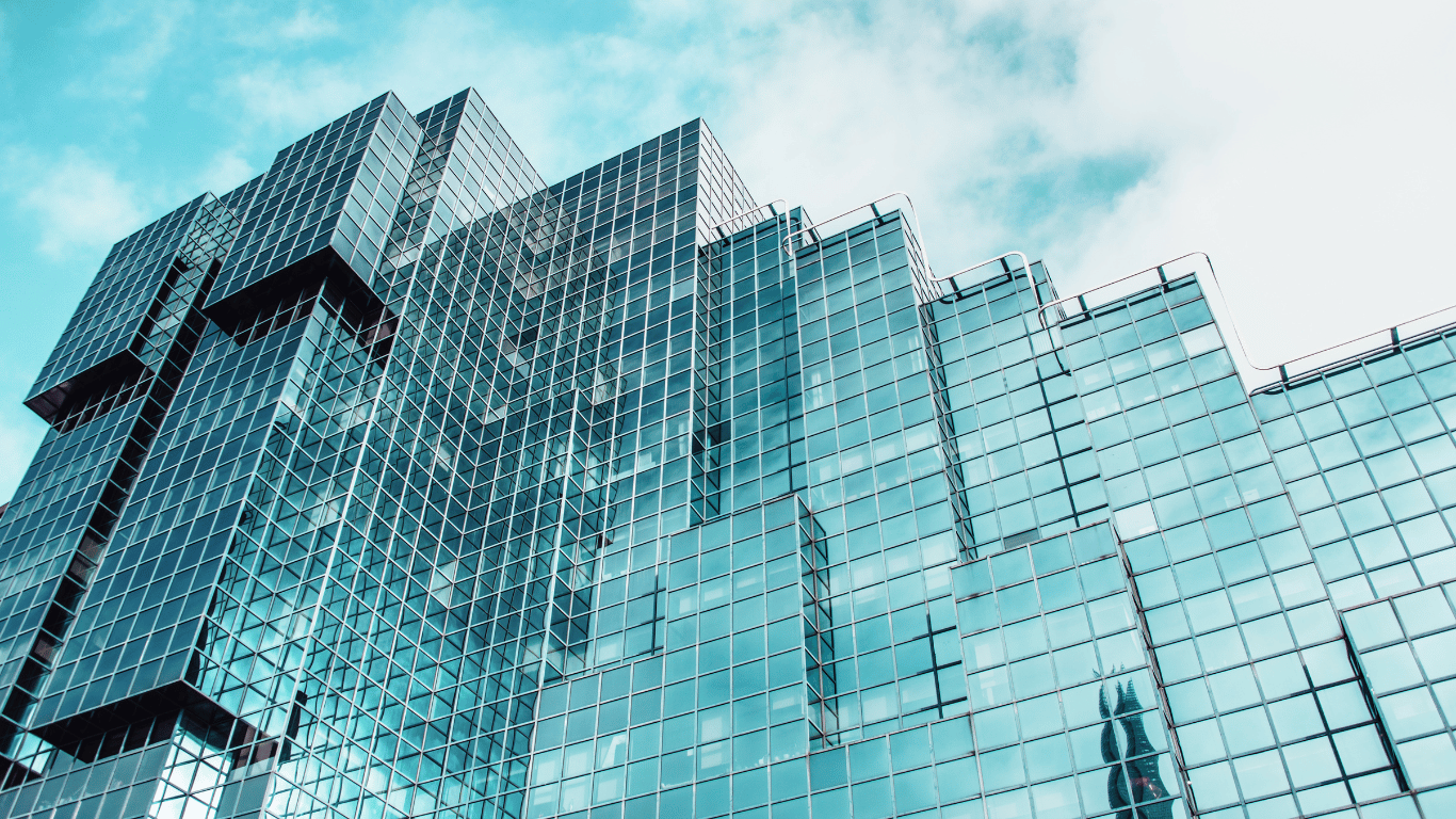 Fachada moderna de um edifício comercial com Preço de pele de vidro azul refletindo o céu.