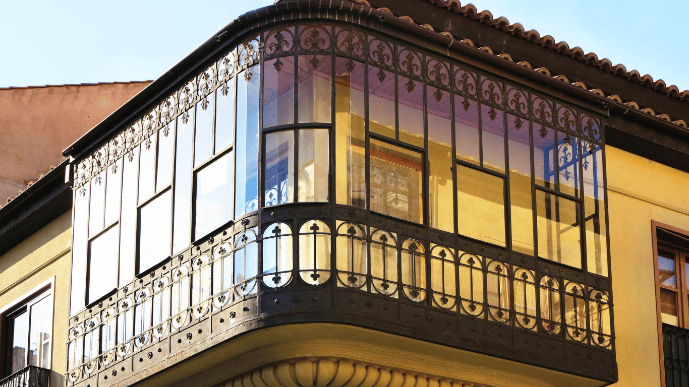 Varanda com acabamento de vidro em sistema glazing e detalhes em ferro trabalhado.