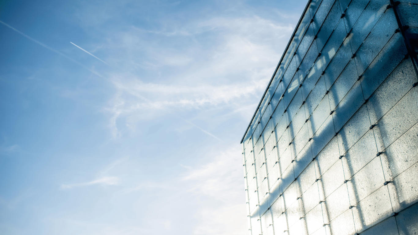 Cobertura retrátil de vidro em estrutura moderna, refletindo o céu azul.