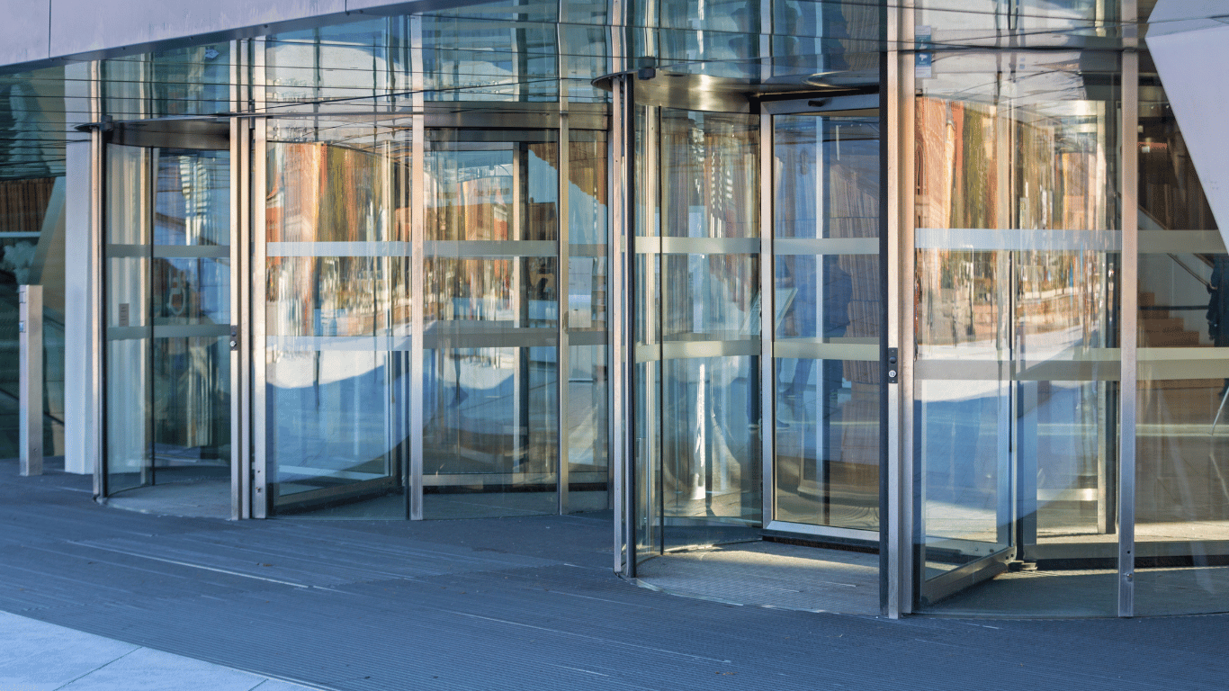 Porta de entrada com cobertura de vidro e estrutura moderna em edifício comercial.